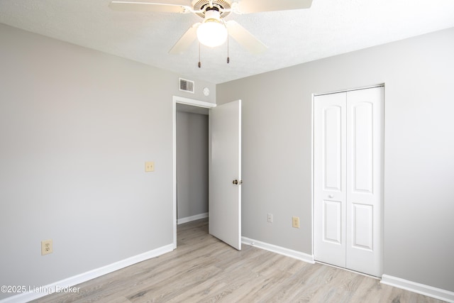 unfurnished bedroom featuring a closet, visible vents, light wood-style flooring, ceiling fan, and baseboards