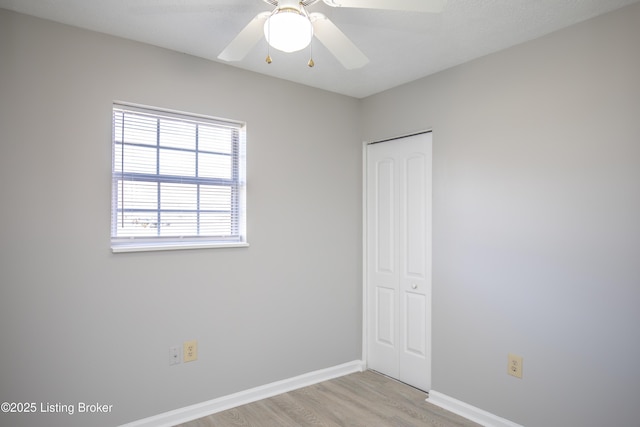 spare room featuring ceiling fan, light wood-style flooring, and baseboards