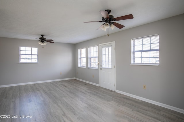 unfurnished room featuring plenty of natural light, a textured ceiling, baseboards, and wood finished floors