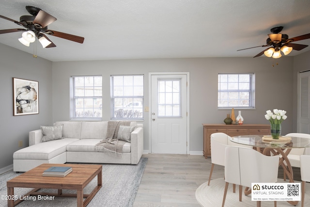 living area featuring baseboards, ceiling fan, and light wood-style floors