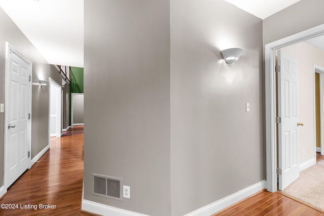 hallway featuring baseboards, visible vents, and wood finished floors