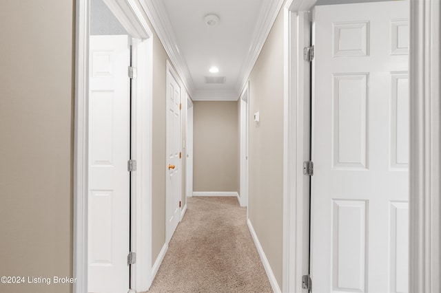 hall featuring light carpet, baseboards, visible vents, and crown molding