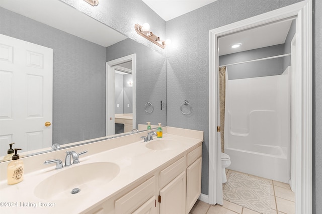 bathroom featuring double vanity, a sink, toilet, and tile patterned floors