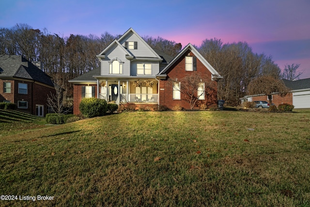 traditional-style home featuring a porch, brick siding, and a yard