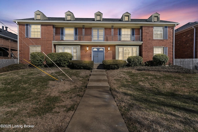 view of front of property featuring a balcony and a yard