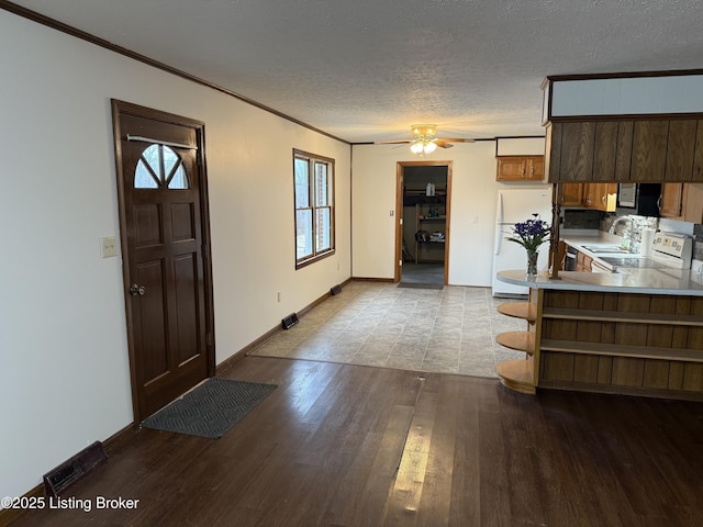 kitchen featuring crown molding, a textured ceiling, kitchen peninsula, white appliances, and light hardwood / wood-style floors