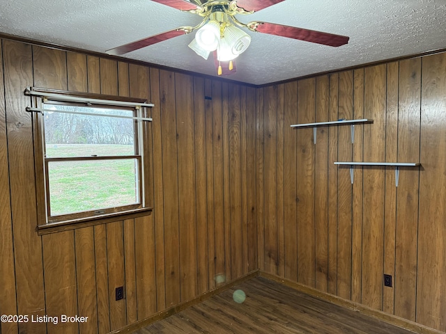 empty room featuring dark hardwood / wood-style floors, a textured ceiling, and wood walls