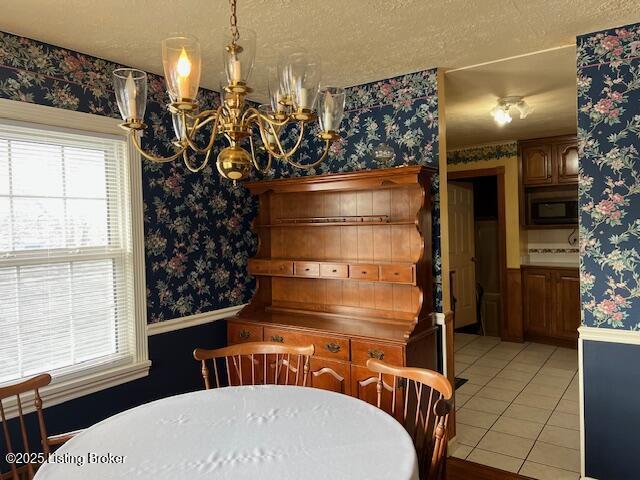 dining space featuring a textured ceiling, light tile patterned flooring, a chandelier, and wallpapered walls