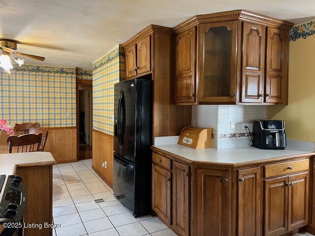 kitchen featuring freestanding refrigerator, light countertops, ceiling fan, and a wainscoted wall
