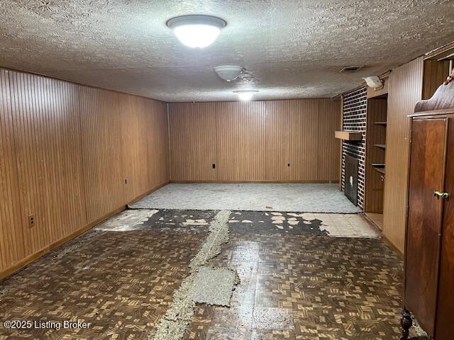 finished below grade area featuring wooden walls and a textured ceiling