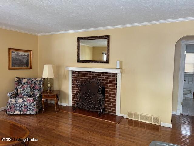 living area with arched walkways, a textured ceiling, visible vents, and wood finished floors