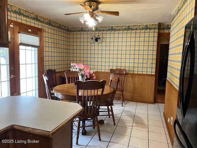 dining area with french doors, a wainscoted wall, a ceiling fan, wallpapered walls, and light tile patterned floors