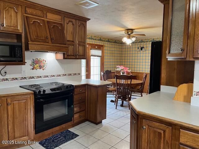 kitchen featuring wallpapered walls, light countertops, a ceiling fan, light tile patterned floors, and black appliances