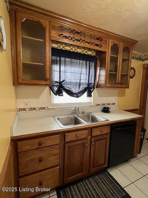 kitchen featuring a sink, black dishwasher, light tile patterned flooring, and light countertops