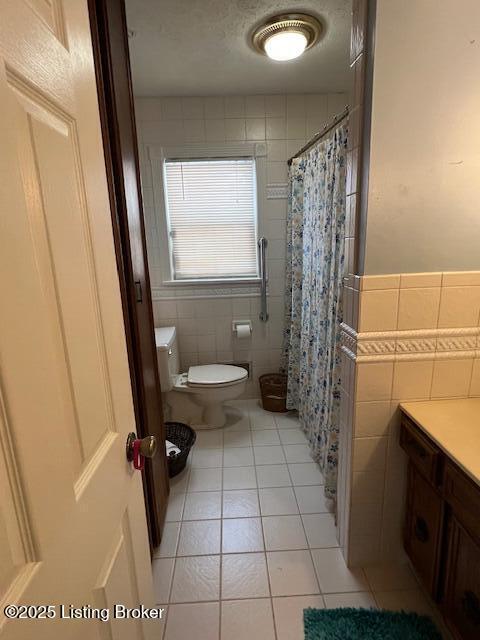 full bathroom with a shower with curtain, tile walls, toilet, and tile patterned floors