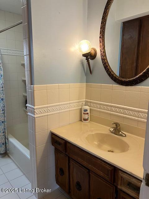full bathroom with tile walls, tile patterned flooring, wainscoting, vanity, and shower / bathtub combination with curtain