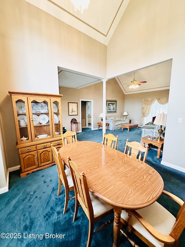 carpeted dining area with ceiling fan, high vaulted ceiling, and decorative columns