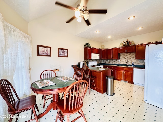 kitchen featuring sink, white appliances, ceiling fan, backsplash, and kitchen peninsula