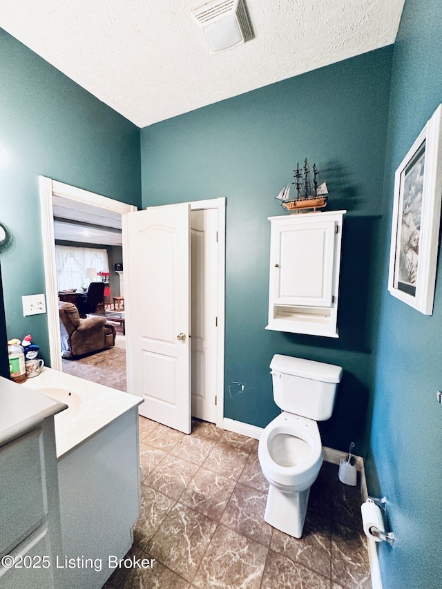 bathroom featuring vanity, a textured ceiling, and toilet