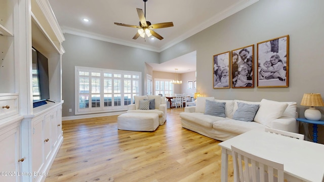 living area featuring light wood-type flooring, recessed lighting, ornamental molding, and ceiling fan with notable chandelier