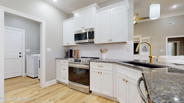 kitchen featuring light wood finished floors, tasteful backsplash, visible vents, appliances with stainless steel finishes, and a sink