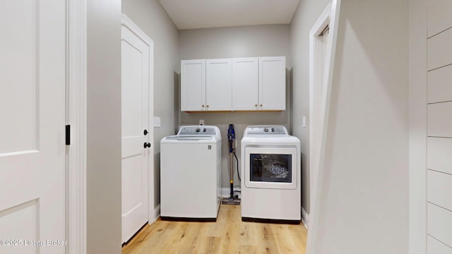 clothes washing area featuring light wood-type flooring, cabinet space, and separate washer and dryer