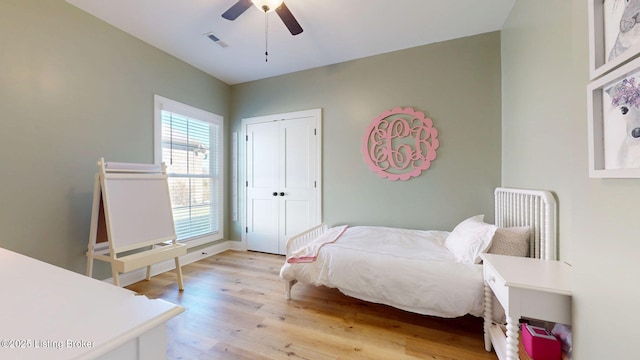 bedroom with light wood finished floors, ceiling fan, visible vents, and a closet