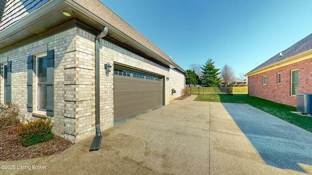 view of home's exterior with brick siding, a lawn, fence, and central air condition unit