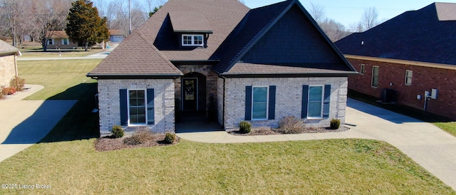 view of front of home with a shingled roof, a front yard, and brick siding