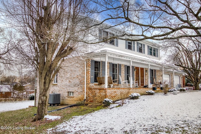 view of front of home with covered porch, central AC, and a garage