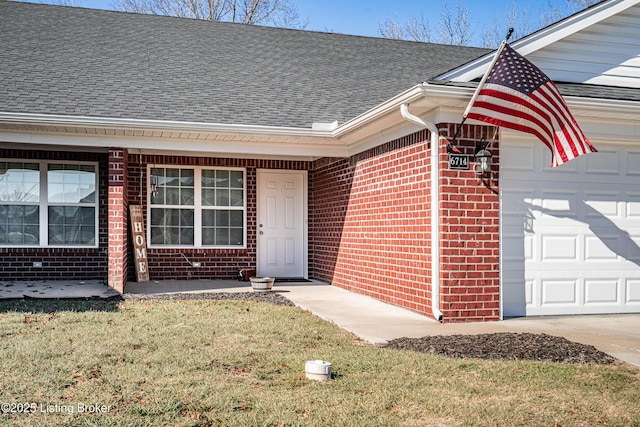 doorway to property with a garage and a lawn