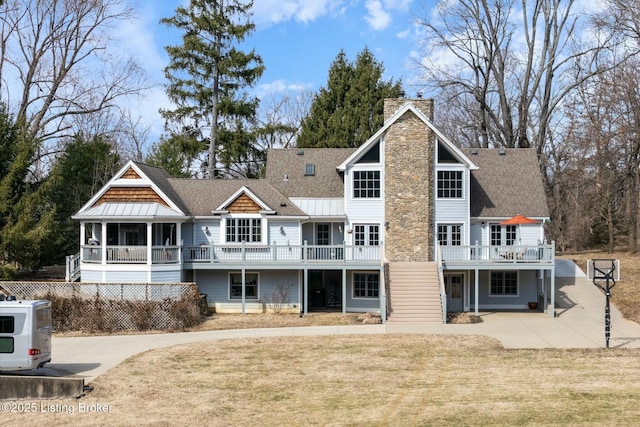 back of property featuring a yard, a patio, a shingled roof, and a chimney