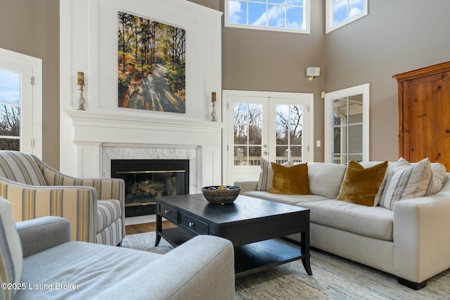 living room featuring french doors, a fireplace, wood finished floors, and a towering ceiling