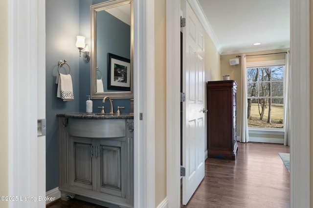 hallway with baseboards, ornamental molding, dark wood-style flooring, and a sink