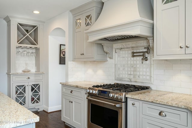 kitchen with white cabinets, glass insert cabinets, gas range, and custom range hood