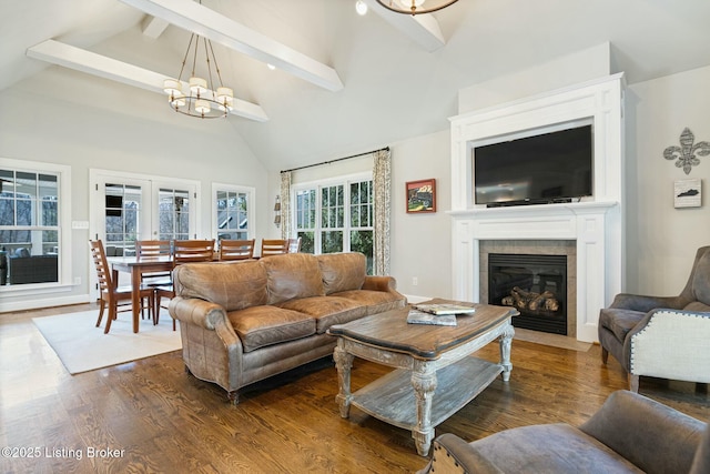 living area featuring a tiled fireplace, dark wood-type flooring, beam ceiling, high vaulted ceiling, and a notable chandelier