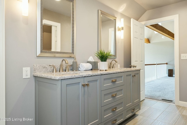 full bathroom featuring vaulted ceiling, double vanity, a sink, and baseboards