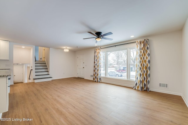 unfurnished living room with light wood finished floors, baseboards, stairs, and visible vents