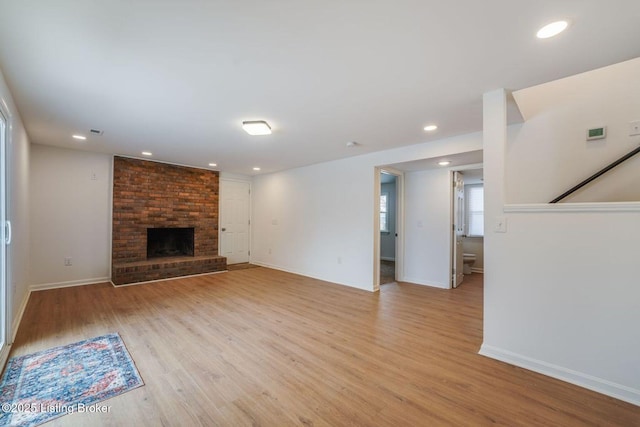 unfurnished living room with light wood-type flooring, a brick fireplace, and recessed lighting