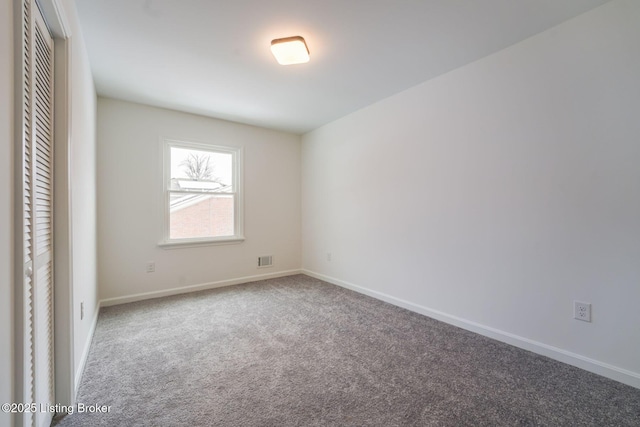 empty room with carpet, visible vents, and baseboards