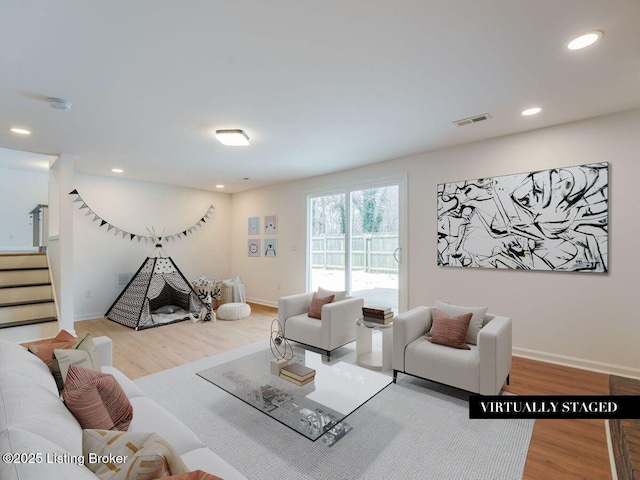 living area featuring recessed lighting, visible vents, wood finished floors, baseboards, and stairs