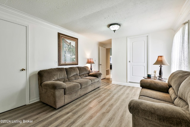 living room with crown molding, wood-type flooring, and a textured ceiling