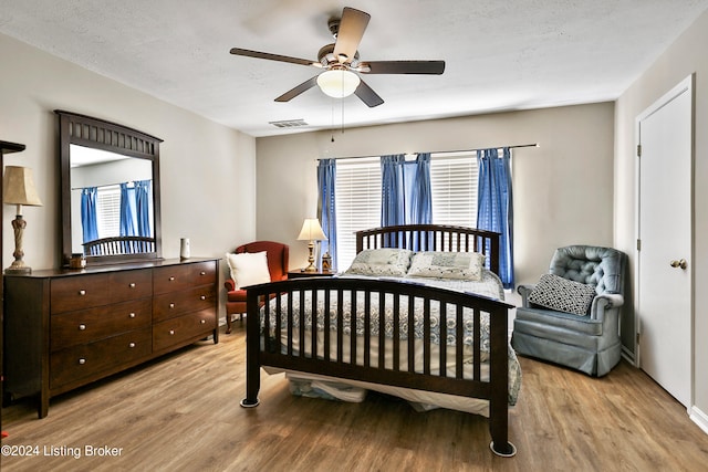 bedroom featuring ceiling fan, light hardwood / wood-style floors, and a textured ceiling