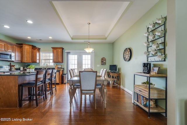 dining area featuring sink, dark wood-type flooring, and a raised ceiling