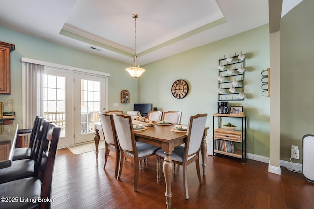 dining area featuring dark hardwood / wood-style floors and a raised ceiling