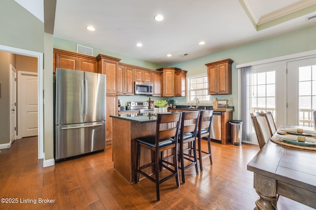 kitchen with appliances with stainless steel finishes, sink, a kitchen island, and dark hardwood / wood-style floors