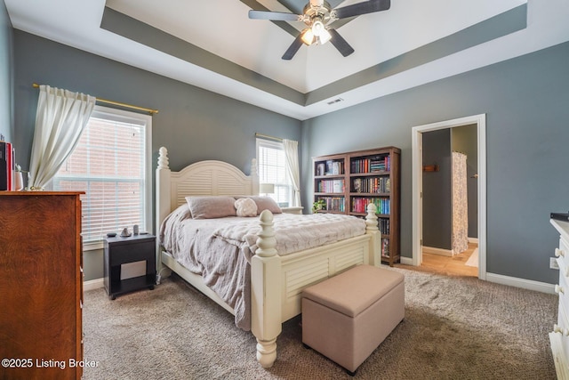 bedroom featuring a tray ceiling, ceiling fan, and light colored carpet