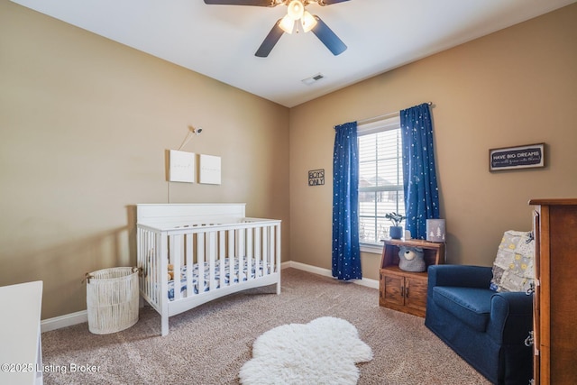 carpeted bedroom with ceiling fan and a nursery area