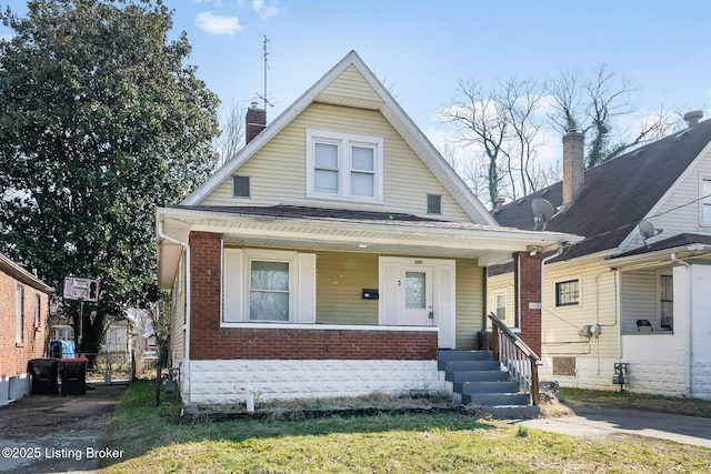 bungalow with covered porch and brick siding