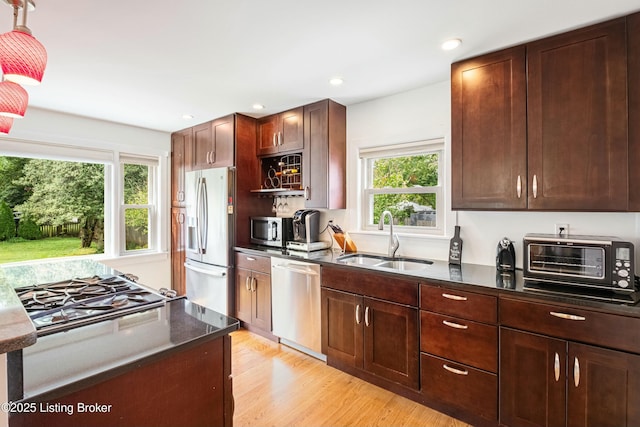 kitchen featuring appliances with stainless steel finishes, sink, and light wood-type flooring